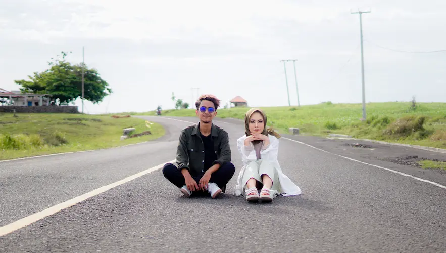 couple-sits-road-front-green-field
